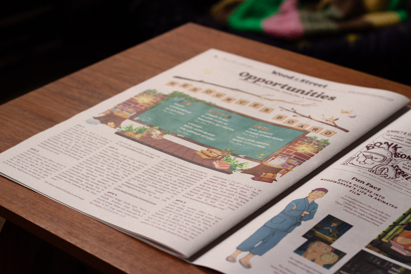 Open newspaper spread on a wooden surface with illustrations and text